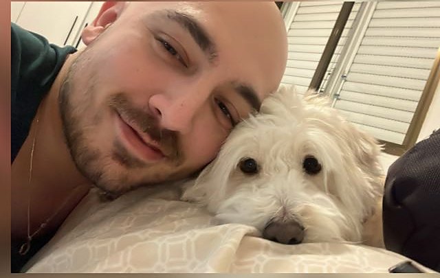 Atalay Aygül smiling next to Mia, a small white dog